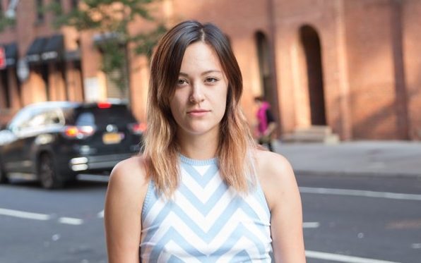 Mulher jovem usa cabelo partido de lado e camiseta com estampa gráfica azul clara