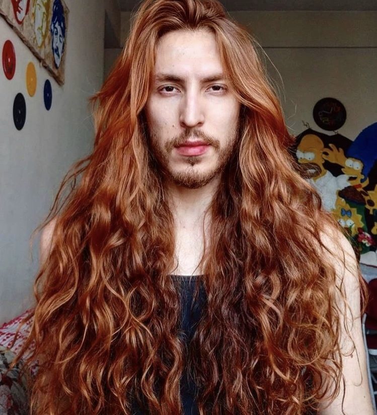 homem de cabelo comprido e ruivo olha para a câmera