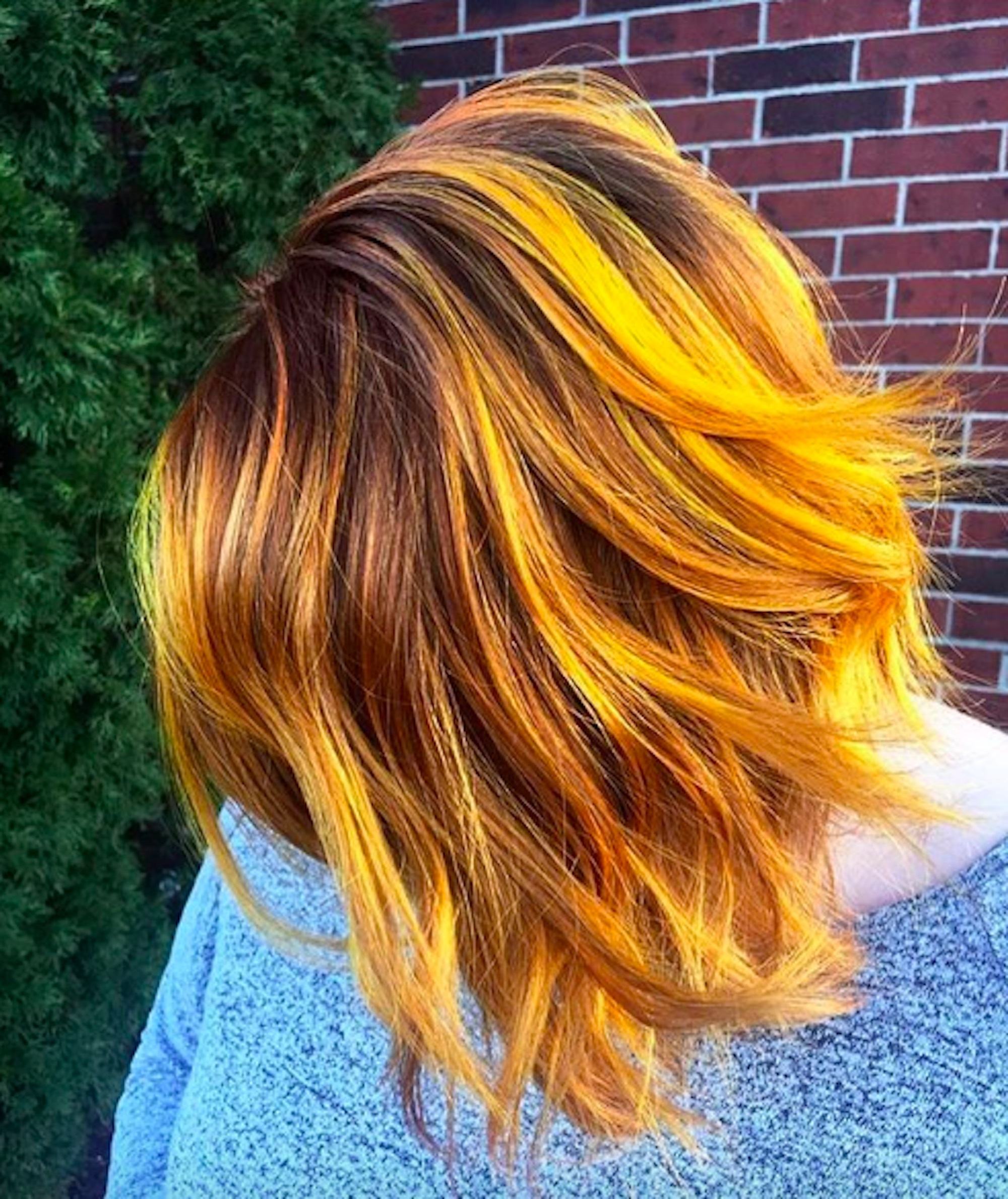 Mulher de cabelos coloridos com mechas laranjas e amarelas