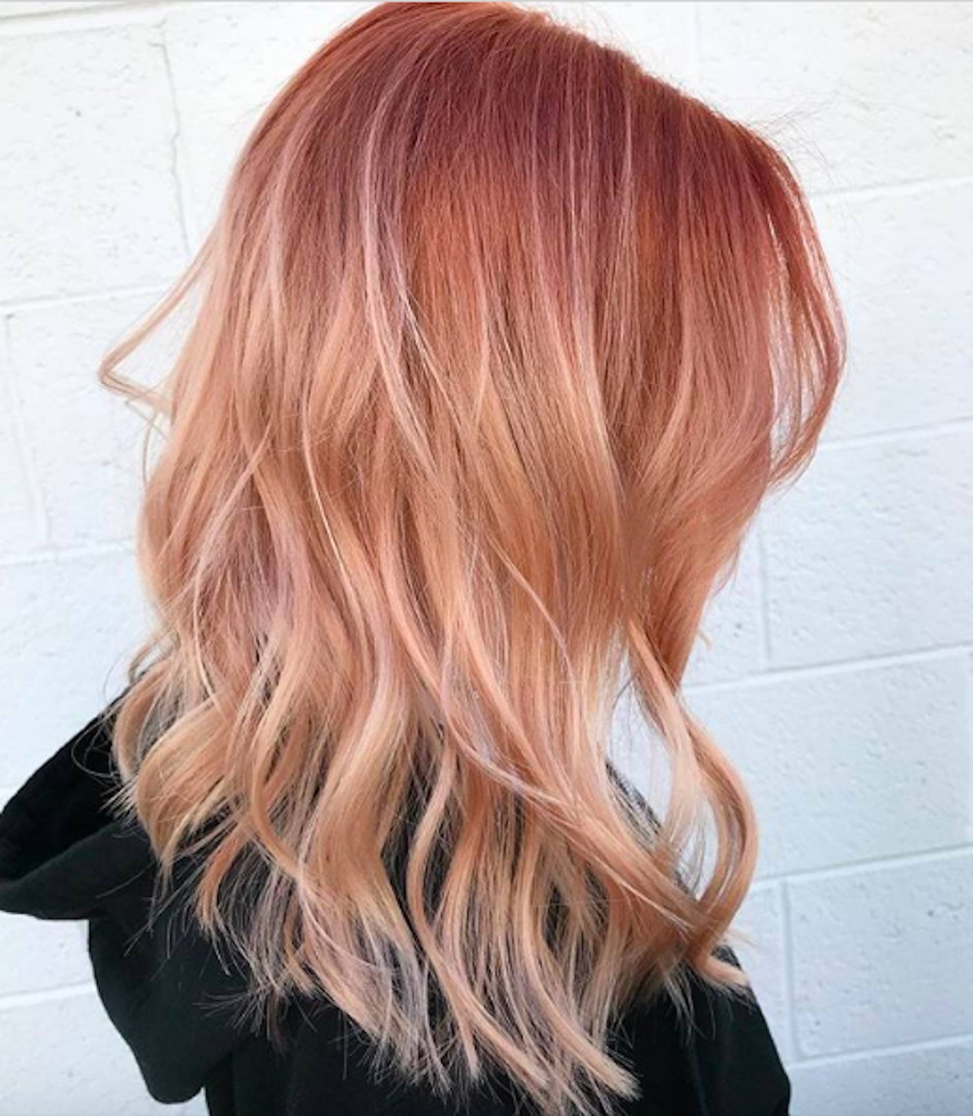 Mulher com cabelos pink lemonade ondulados