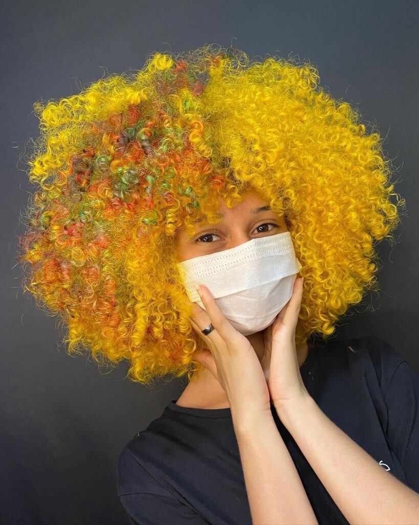 mulher de máscara com cabelo amarelo cacheado