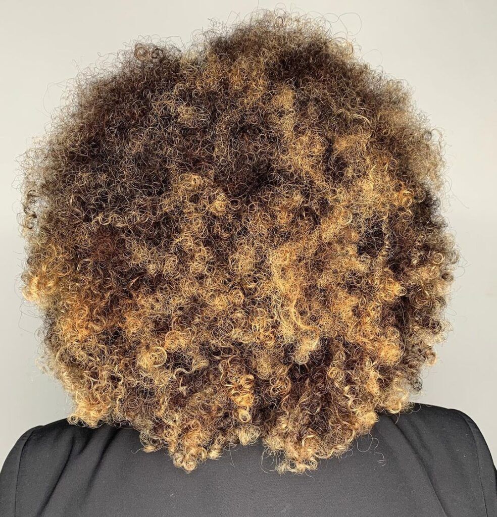 mulher com cabelo castanho iluminado crespo curto dourado