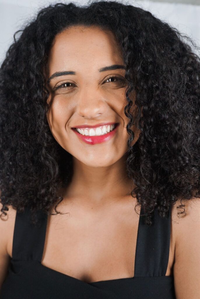 mulher sorrindo com cabelo cacheado médio castanho