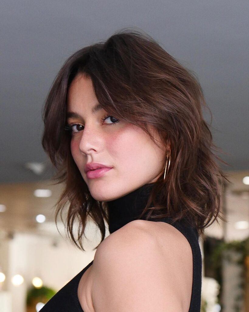 Mulher posa com corte de cabelo com franja bardot