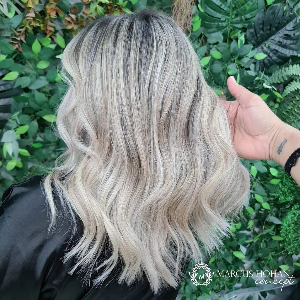 mulher de costas mostra o cabelo perolado com a raiz loiro esfumada
