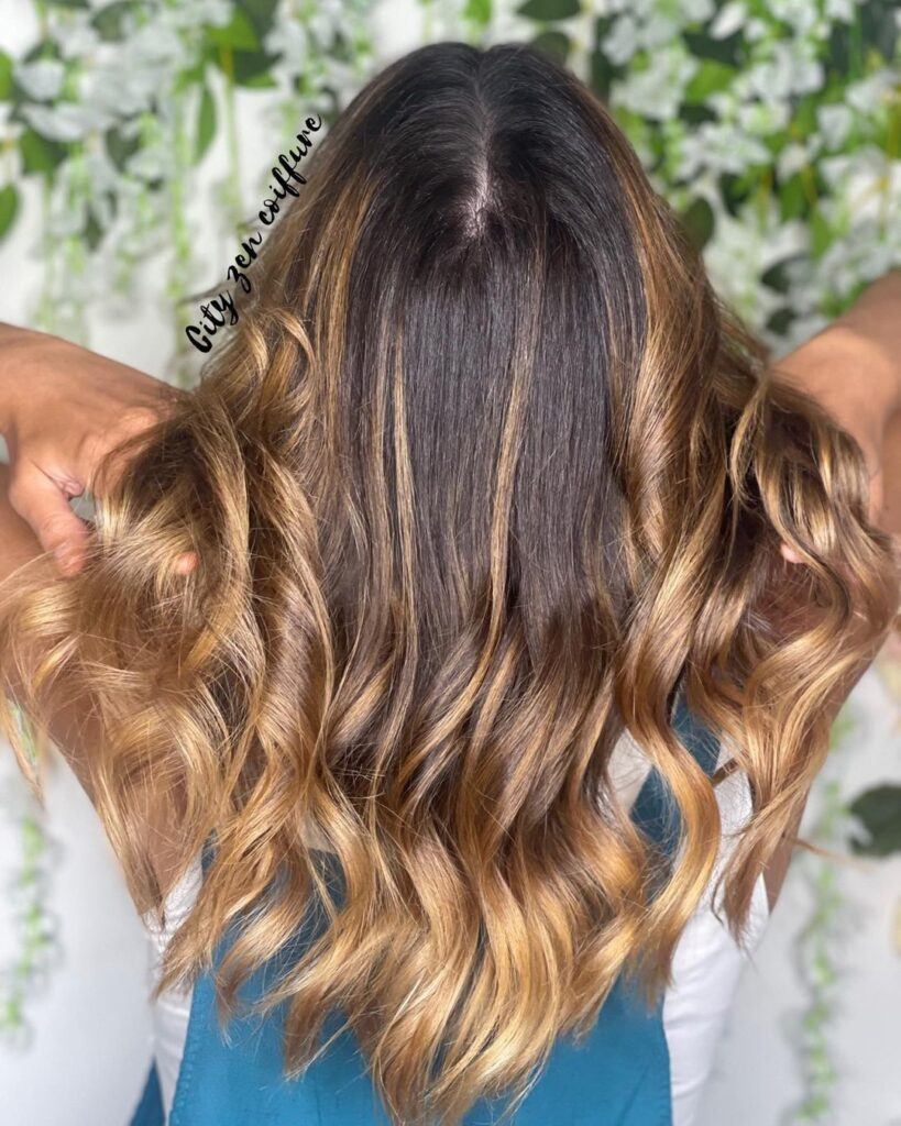 mulher de costas com as mãos no cabelo mostrando o ombré hair mel
