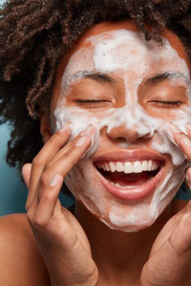 mulher sorrindo com espuma de limpeza no rosto
