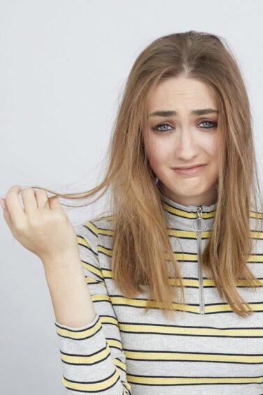 mulher com expressão facial triste segurando o cabelo