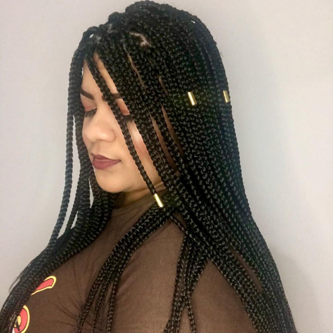Mulher com trança kanekalon posa de perfil com tranças pretas e miçangas