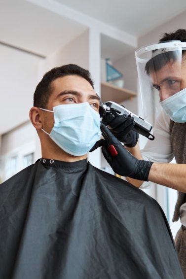 Homem tem o cabelo cortado por cabeleireiro dentro de casa, em sistema delivery