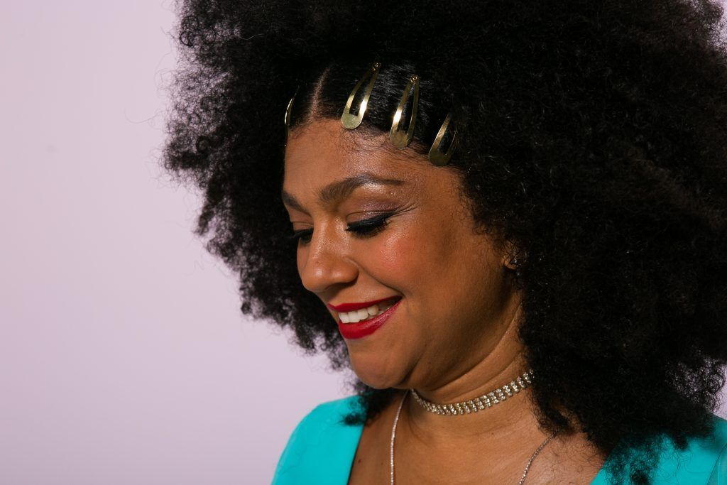 Mulher com cabelo crespo volumoso enfeitado com tic tac de lado