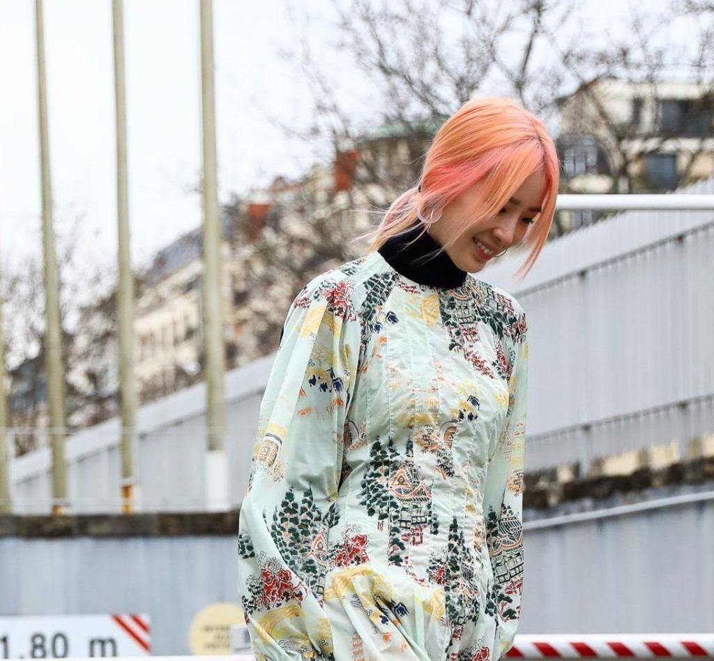 Mulher com cabelo laranja liso e preso num rabo de cavalo baixo