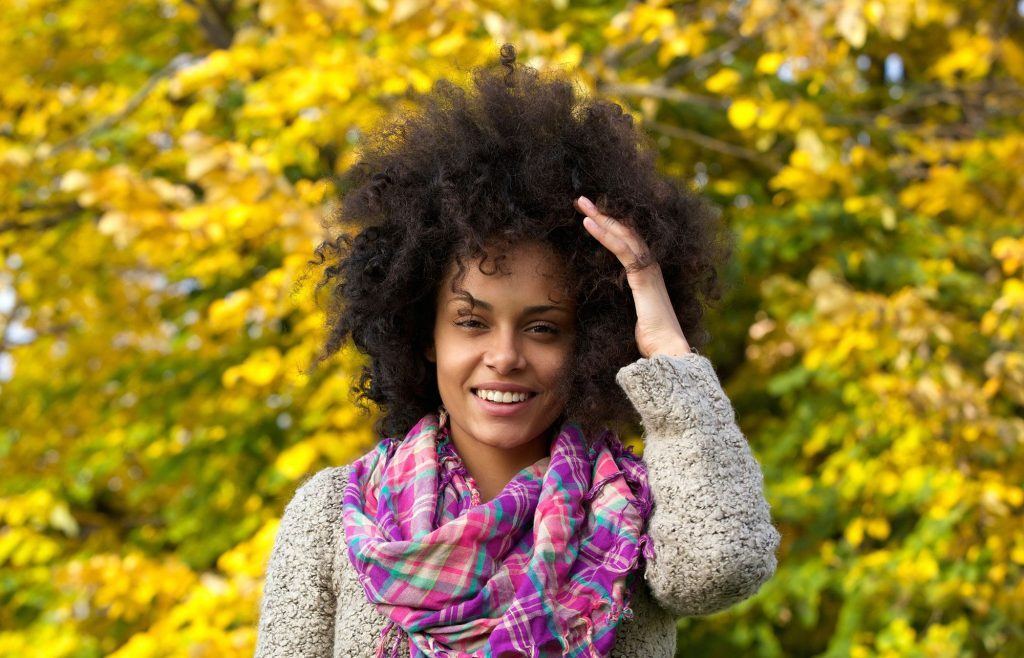 Mulher com cabelo crespo e black power passa a mão nos fios