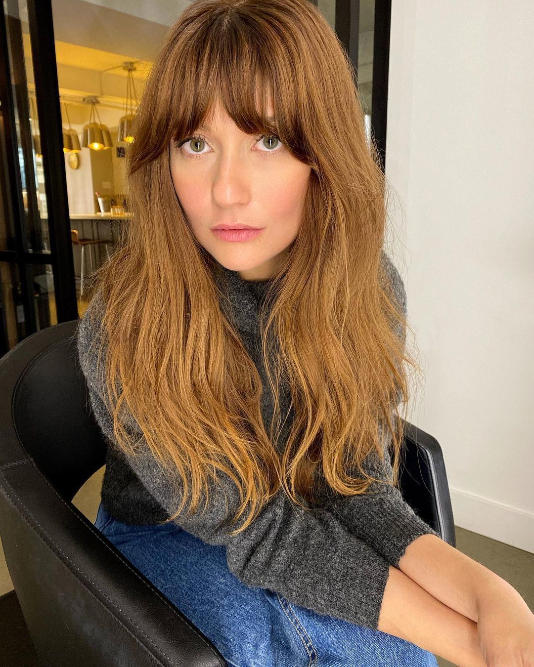Mulher com franja cortina no cabelo longo e castanho-avermelhado