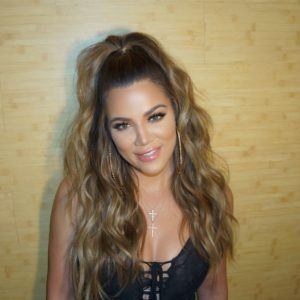 Khloe Kardashian com os cabelos castanhos longos e enrolados