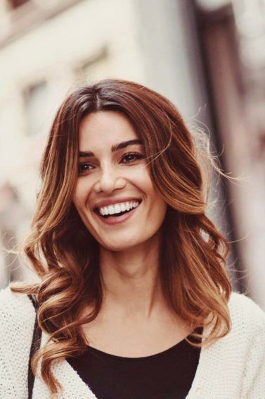 modelo sorrindo com cabelo ondulado castanho: o que nao fazer no cabelo