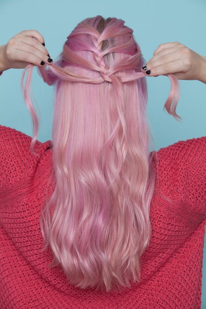 Mulher com cabelos cor-de-rosa fazendo trança escama de peixe