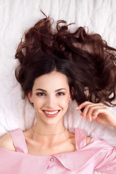 mulher deitada na cama com cabelo brilhante