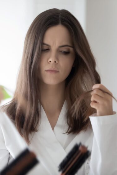 mulher olhando para o cabelo com pontas duplas