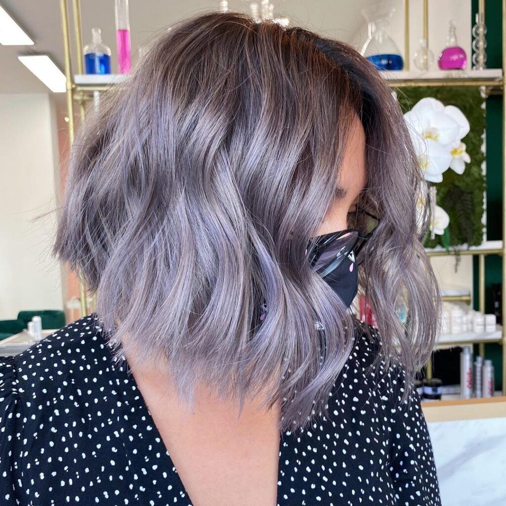 Mulher no salão de perfil com roupa preta e branca e cabelo loiro acinzentado no corte chanel dentro da paleta inverno profundo ou escuro