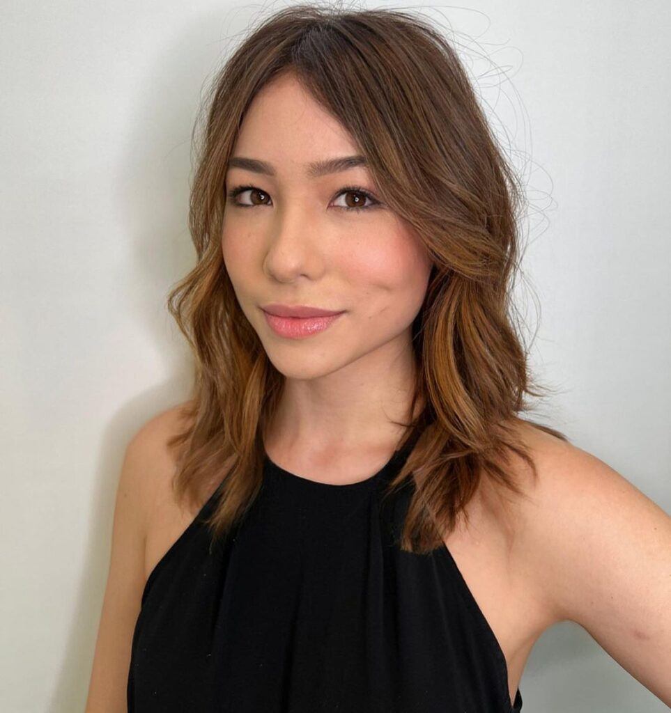 Mulher de blusa preta e cabelo médio loiro escuro na paleta de cores inverno profundo