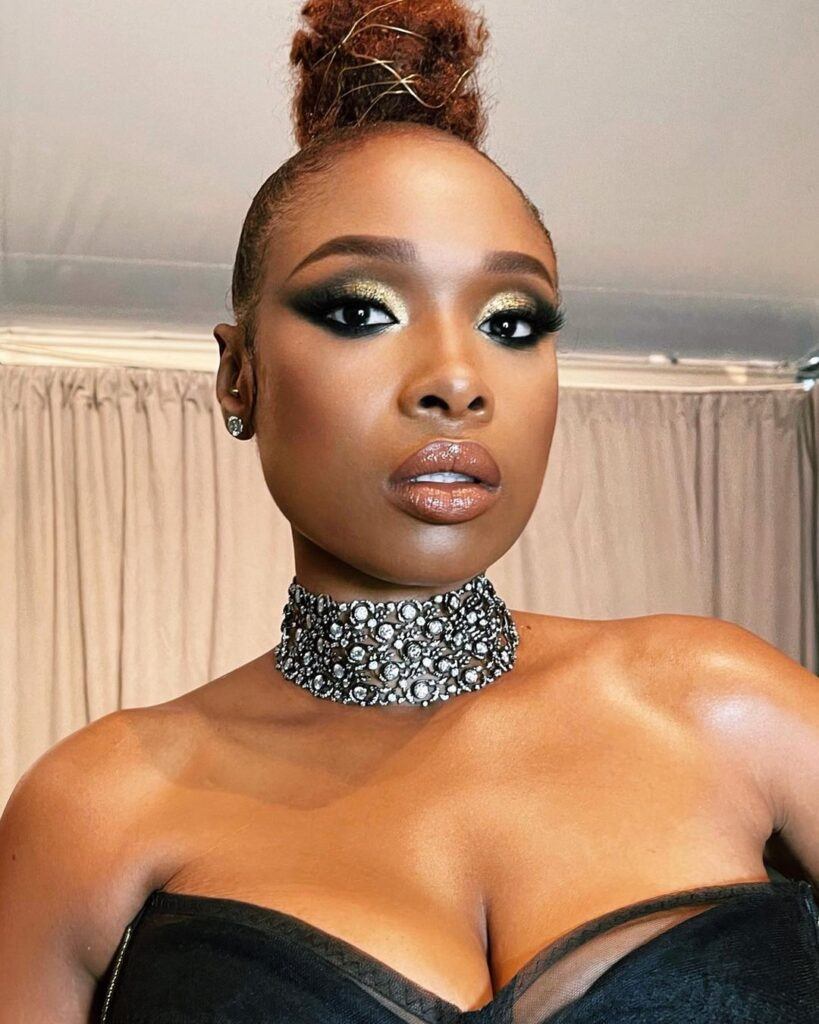 Atriz e cantora Jennifer Hudson posa maquiada e com o cabelo puxado para cima num coque, evidenciando o rosto triangular
