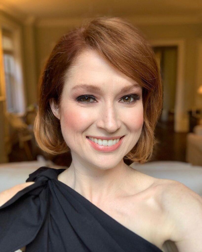 Atriz Ellie Kamper posa com vestido preto e cabelo ruivo curto chanel no rosto triangular