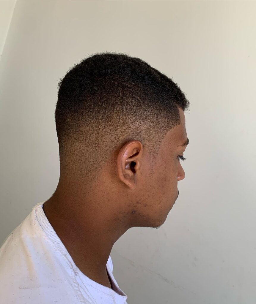 Homem de perfil no salão com camiseta branca e corte degrade no cabelo estilo corte americano ou do jaca