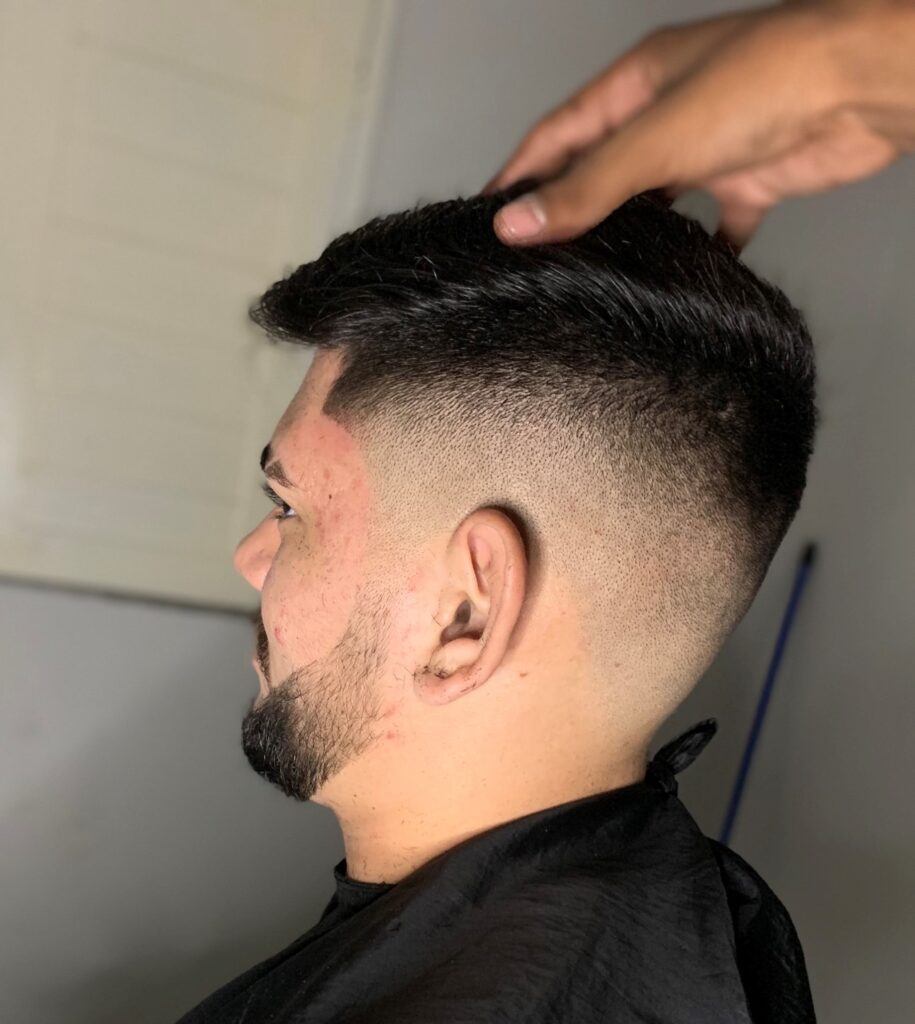 Homem de perfil no salão com corte degrade no cabelo liso