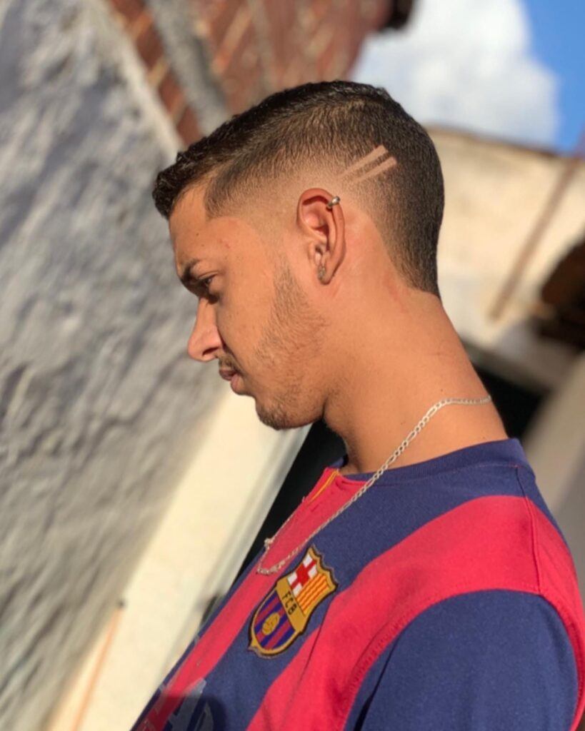 Homem ao ar livre com camiseta do Barcelona e corte moicano degradê no cabelo