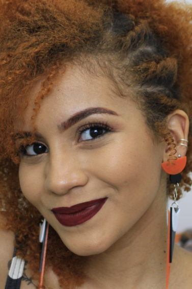 Mulher com cabelo ruivo crespo com penteado preso na lateral