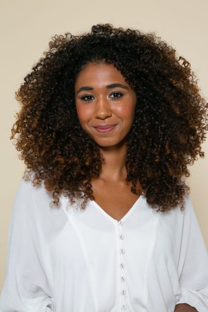 Modelo com cabelo crespo médio para fazer penteado preso na lateral com o cabelo solto