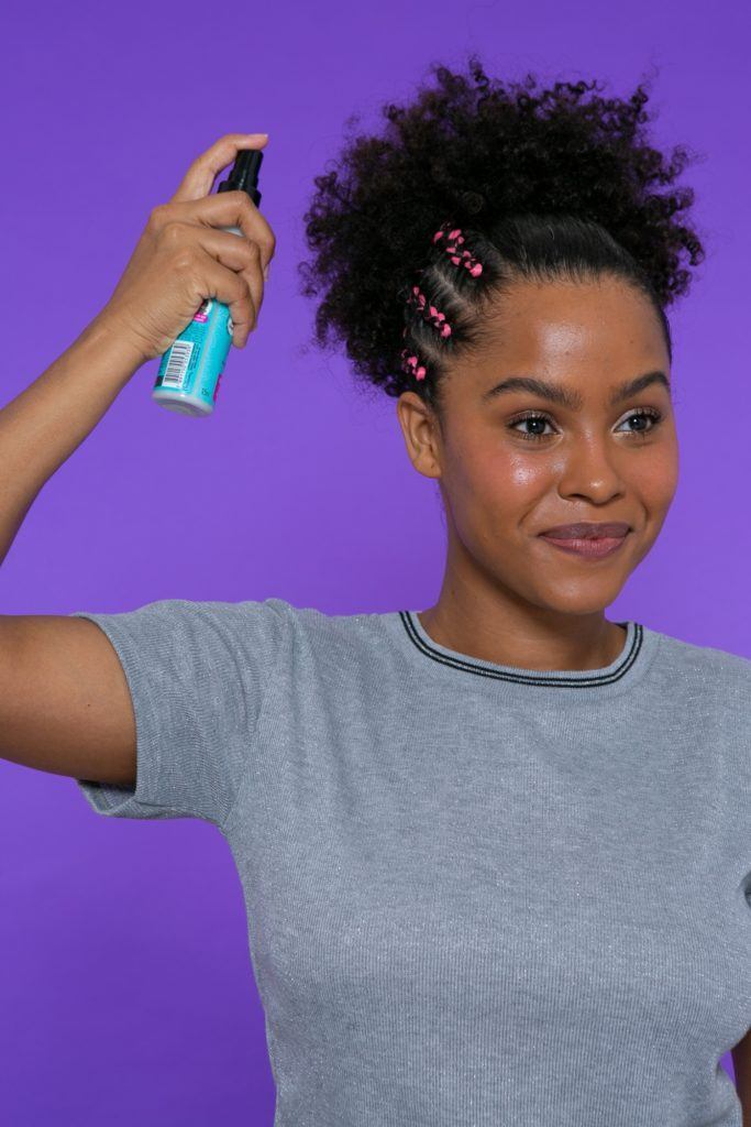modelo de cabelo crespo com rabo de cavalo aplicando o Spray Seda Boom Day After