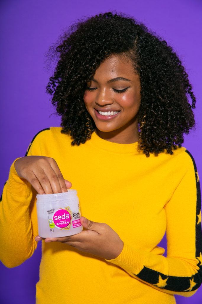 Cabelo cacheado sendo hidratado com creme seda