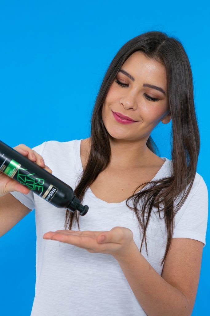 Modelo aplica produto no cabelo para fazer trança de princesa
