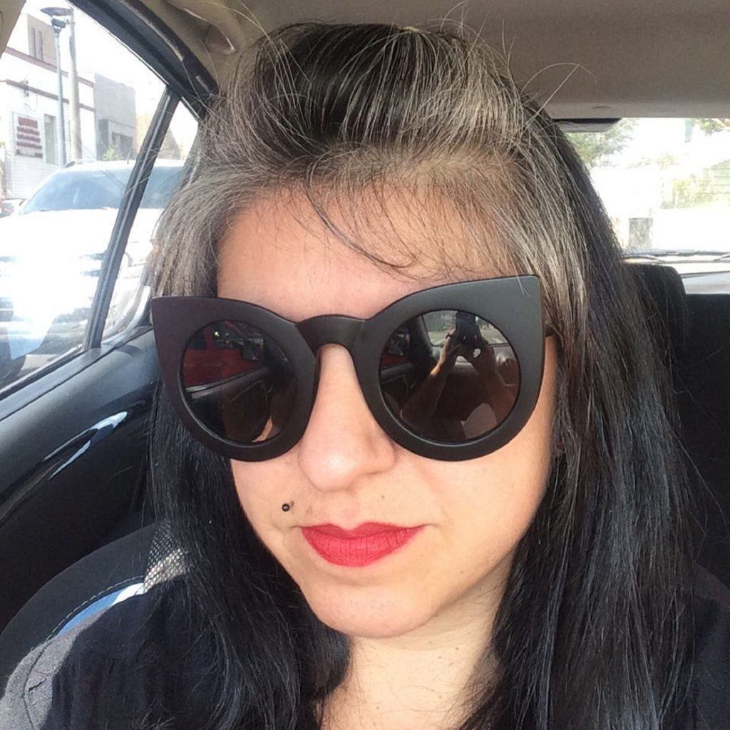 Mulher com cabelo preto liso e mecha loira no topete