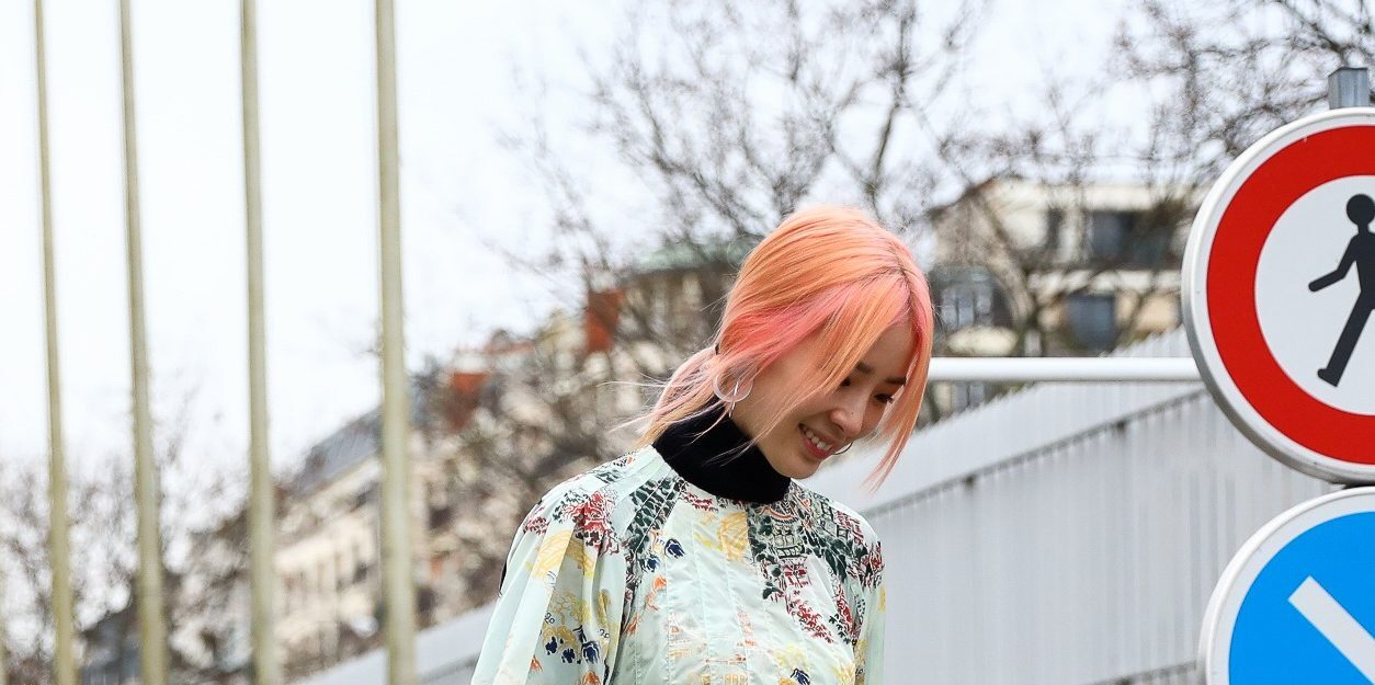 Mulher usa cabelo rosa e anda pela rua com vestido verde água