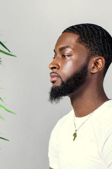 homem de lado com barba e cabelo curto crespo