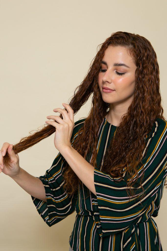 Modelo aplicando produto no cabelo