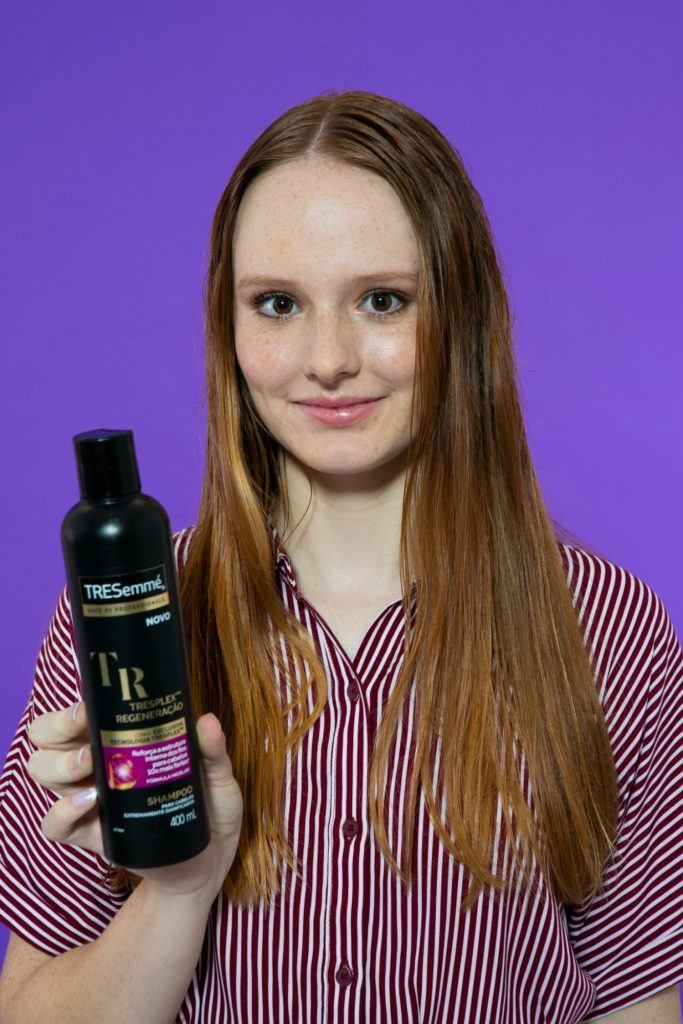 Modelo de cabelo longo e liso. Ela segura o Shampoo TRESemmé Tresplex Regeneração