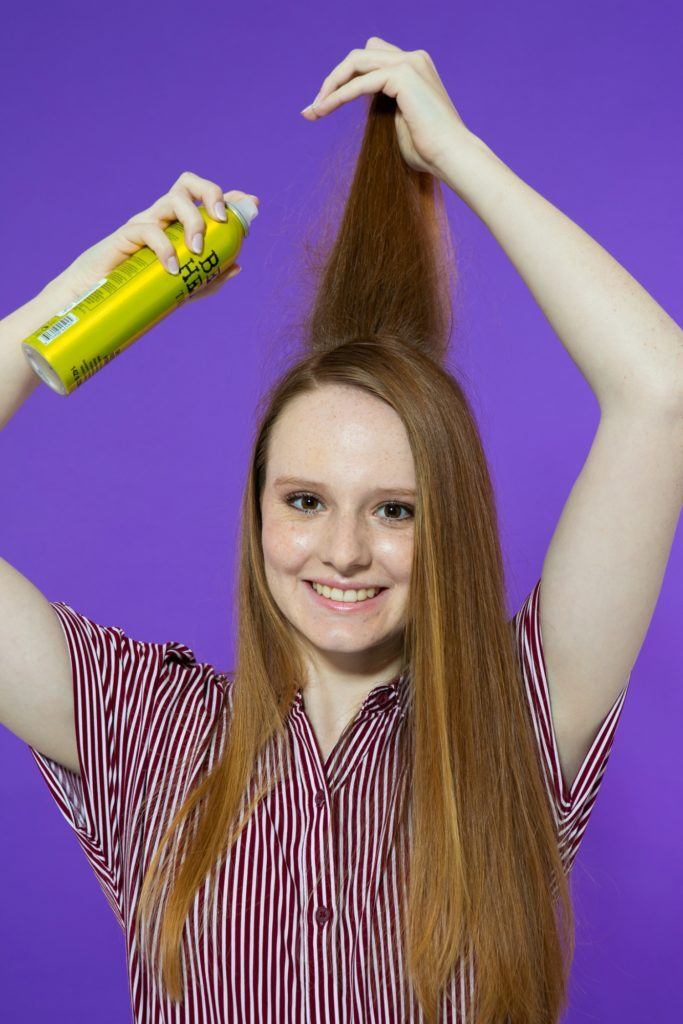 modelo de cabelo longo aplica o shampoo a seco em uma mecha.