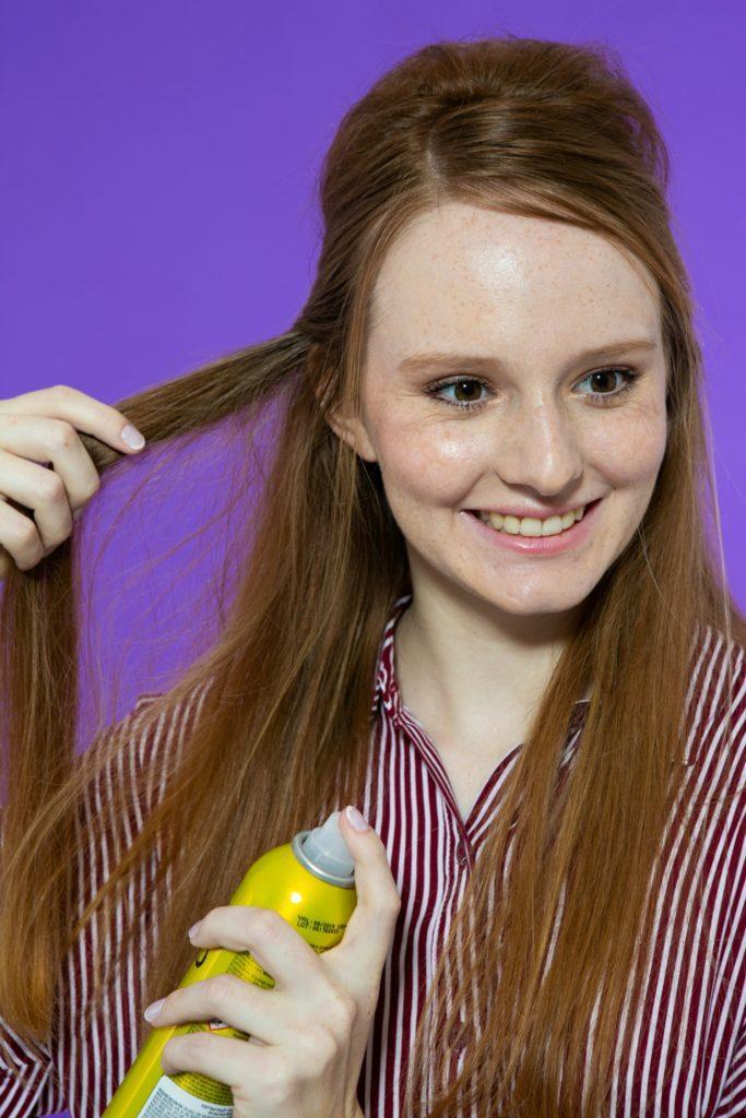 Modelo aplica o Shampoo a Seco Matte Bed Head Oh Bee Hive em uma mecha do cabelo meio preso.