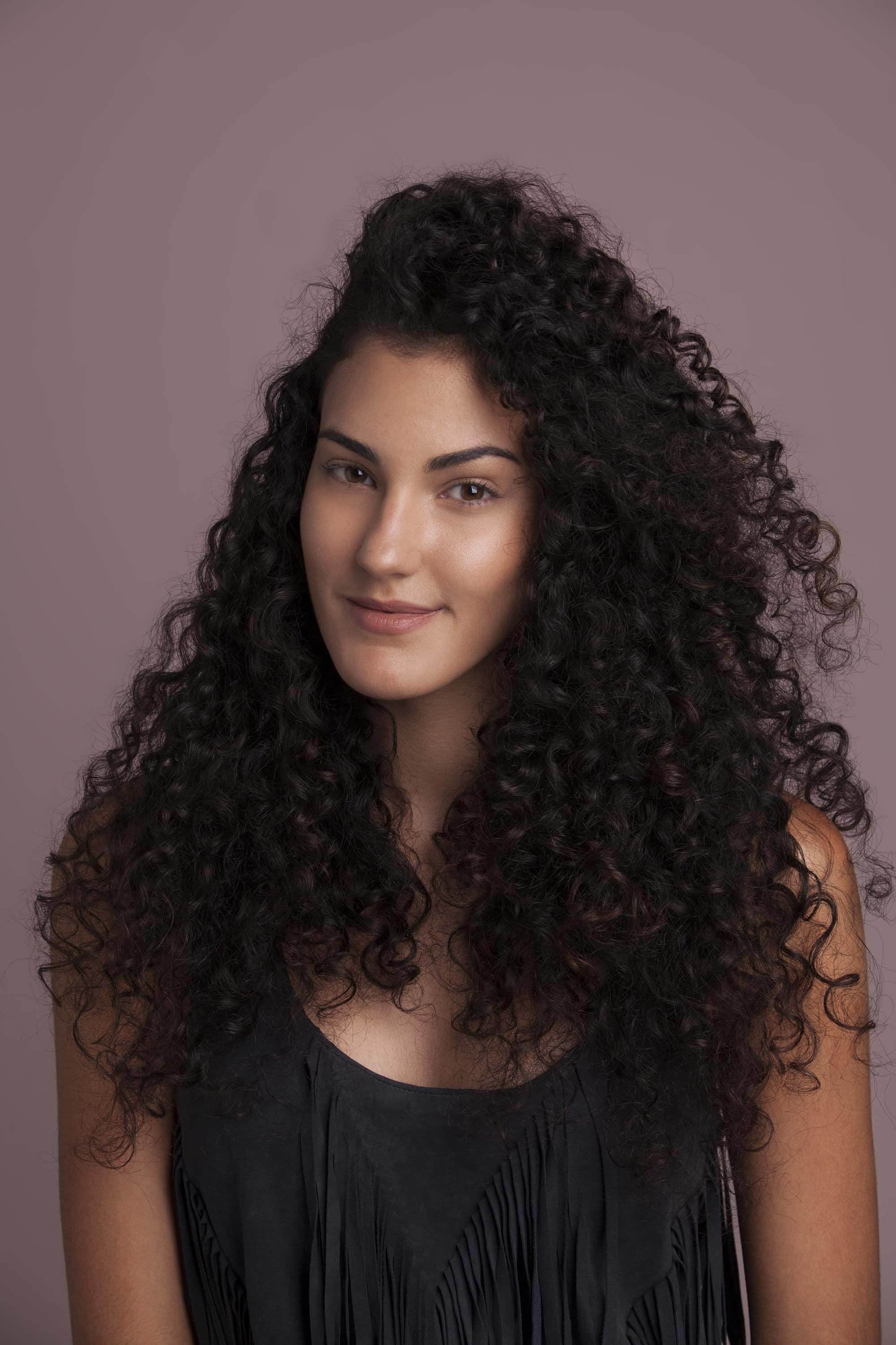 Modelo com cabelo castanho escuro comprido cacheado