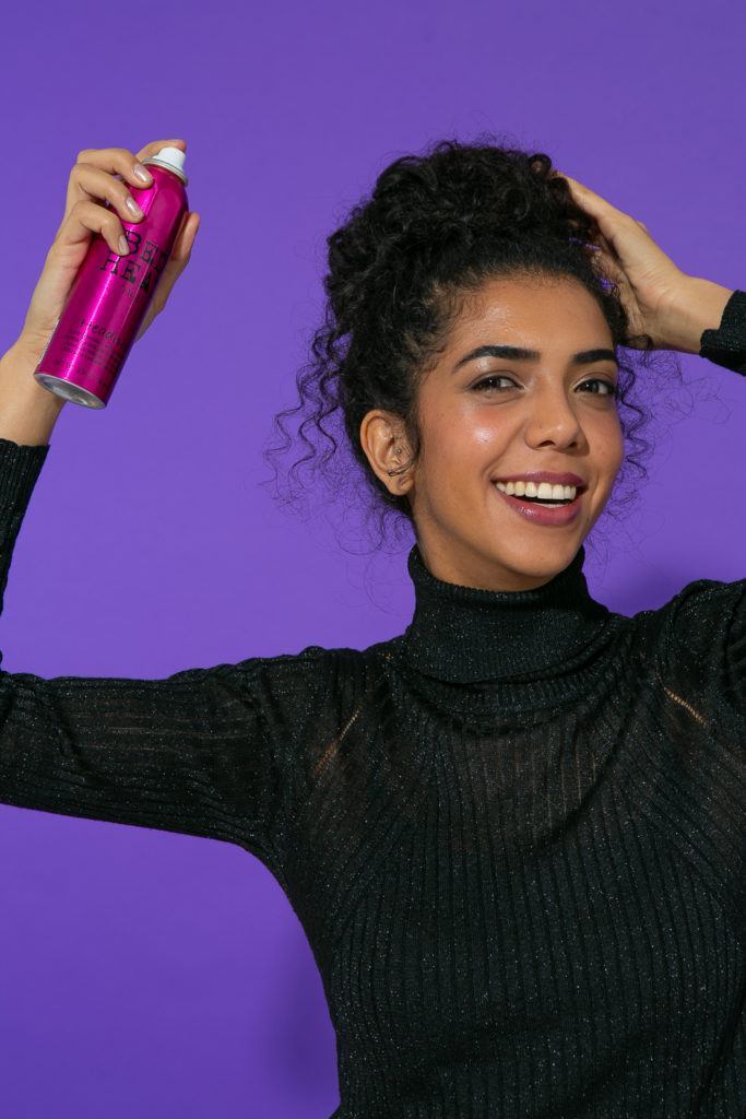 aplicação de spray bed head em cabelo cacheado com coque bagunçado
