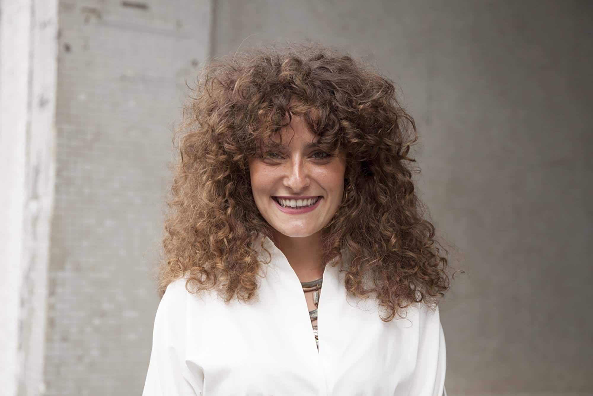 Modelo com cabelo longo cacheado com franja para matéria de corte em camadas com franja