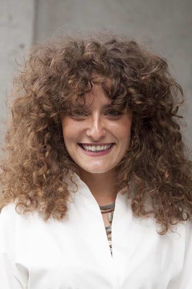 Modelo com cabelo longo cacheado com franja para matéria de corte em camadas com franja