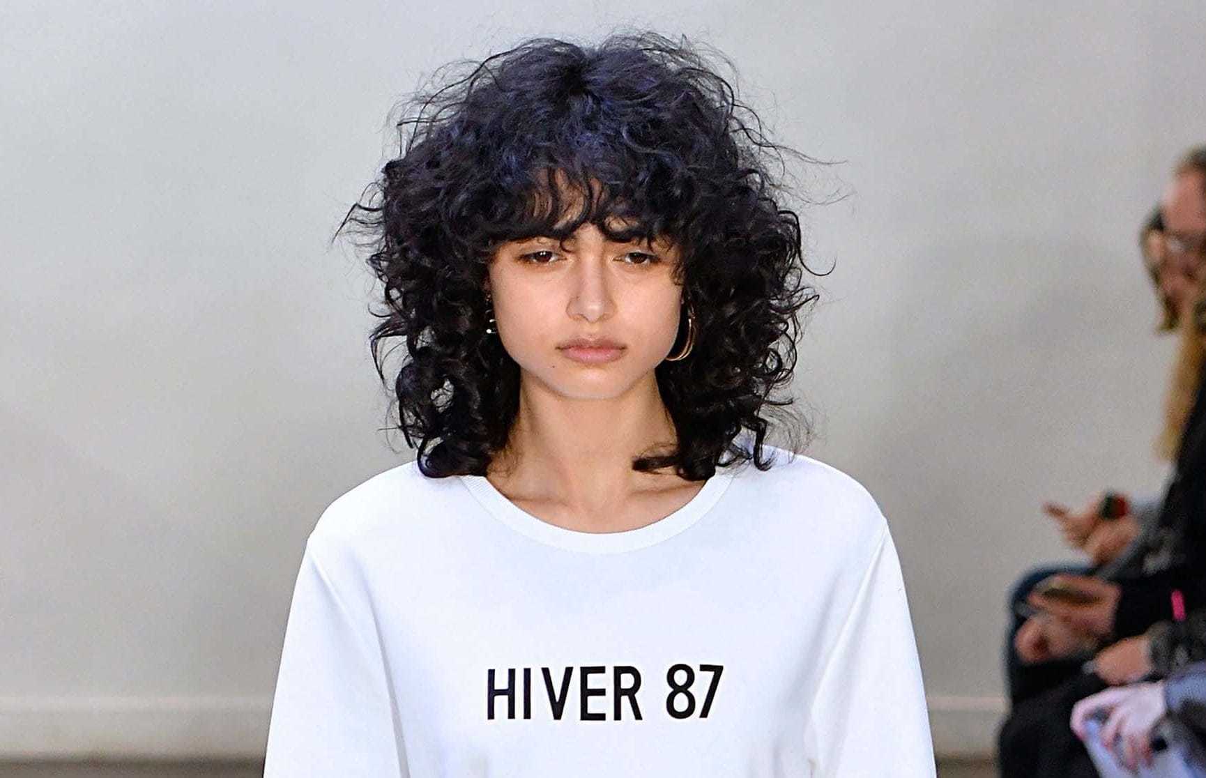Modelo com cabelo castanho de comprimento médio para matéria de corte em camadas com franja