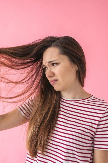 mulher olhando para o cabelo insatisfeita