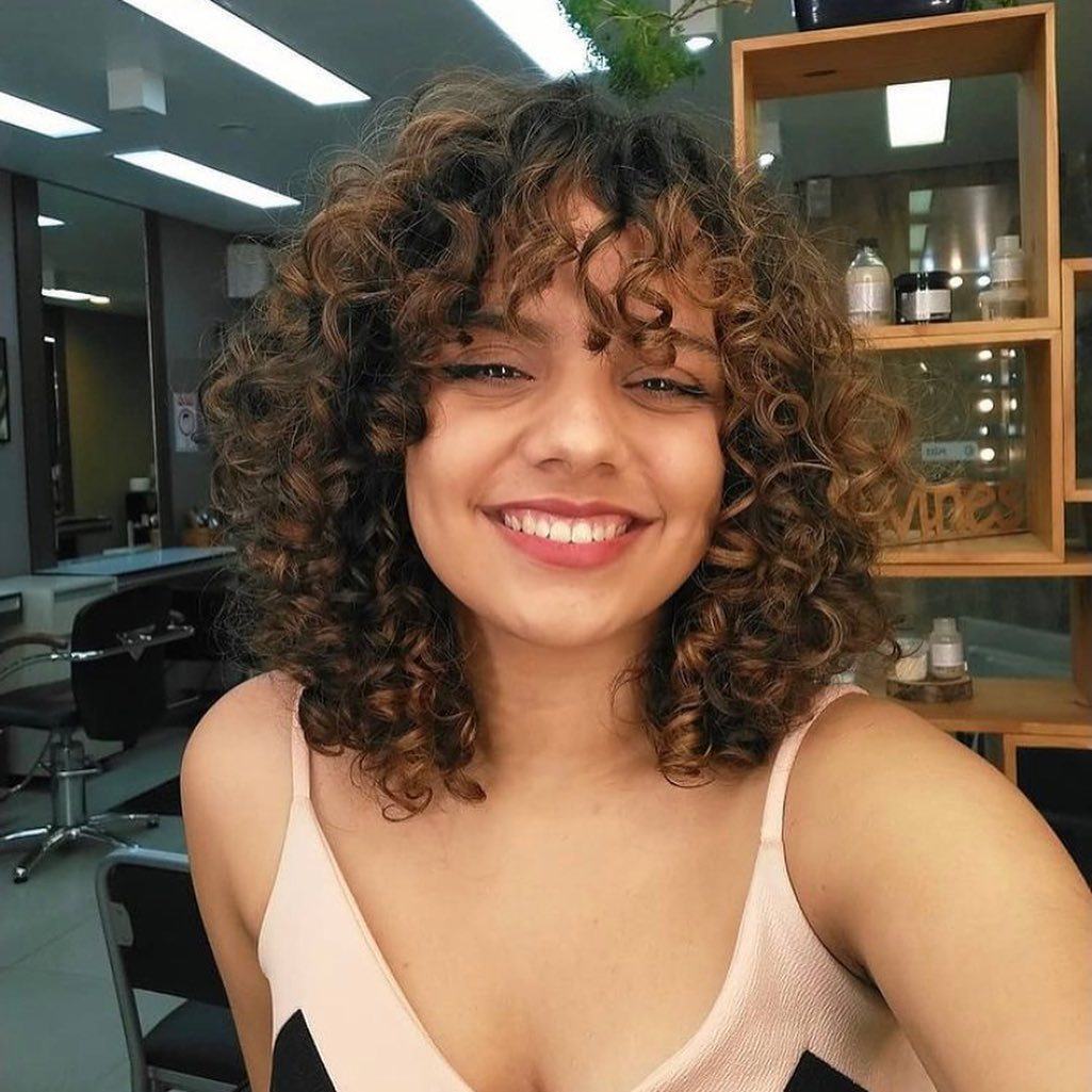franja em cabelo cacheado tipo curtain bangs