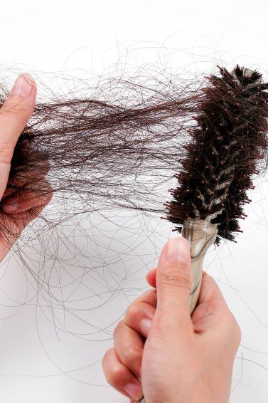 muitos fios de cabelo sendo puxados da escova por uma mão